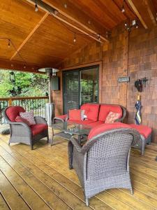 porche con sofá y sillas en la cubierta en Cozy Corner Cottage, en Port Renfrew