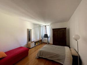 een slaapkamer met een bed en een rode bank bij Grande appartamento in area storica di Bergamo in Bergamo