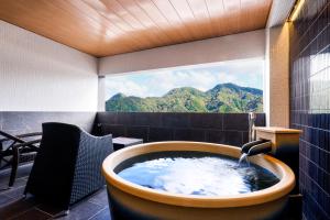 a bath tub in a room with a window at Kawaguchiya Kinosaki Riverside Hotel in Toyooka