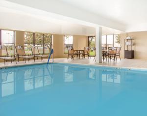 a pool in a hotel with chairs and tables at Holiday Inn Express & Suites - Muncie, an IHG Hotel in Muncie