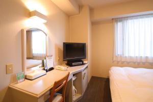 飯田市にあるシルクホテル アネックスのデスク、テレビ、ベッドが備わる客室です。