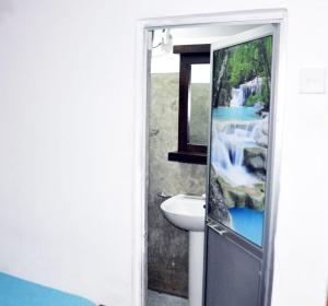La salle de bains est pourvue d'un lavabo et d'une cascade par une porte. dans l'établissement Impress Holiday Home, à Anurâdhapura