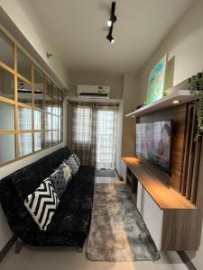 ein Wohnzimmer mit einem schwarzen Sofa und einem Flachbild-TV in der Unterkunft Vanessa’s Place @ Coast Residences Roxas Blvd Pasay in Manila