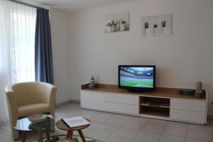 a living room with a television and a chair at Topwohnung für 2 - 3 Personen mit einem getrennten Schlafzimmer in Saas-Almagell