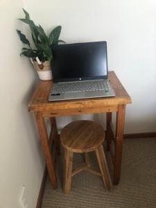 um computador portátil sentado numa mesa de madeira com um banco em Southland Organic Farmstay em Invercargill