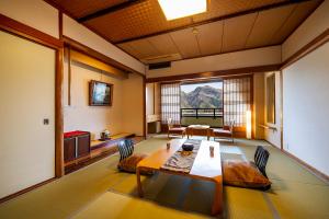 a room with a table and chairs and a large window at Kawaguchiya Kinosaki Riverside Hotel in Toyooka