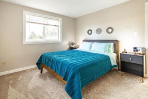 a bedroom with a bed with a blue blanket and a window at THE SHORELINE- Beach Access, Ocean Views, Private in Kodiak