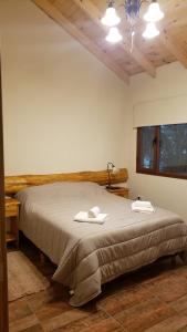 a bedroom with a bed with two towels on it at EL SUSURR0 in Villa Pehuenia