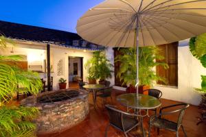 un patio con mesas, sillas y una sombrilla en Casa Pedro Romero, en Cartagena de Indias