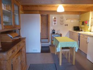 cocina con mesa y cocina pequeña con nevera en Alpenblick nord-ost, en Frutigen