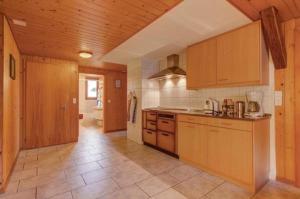 uma cozinha com armários de madeira e piso em azulejo em Balm em Escholzmatt