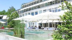 een hotel met een zwembad met parasols bij Tertianum Parkresidenz - moderne 25 Zimmer Wohnung direkt am Zürichsee in Meilen