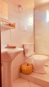 uma casa de banho branca com um lavatório e um WC em Boa Vibe Complexo Rosa Norte na Praia do Rosa
