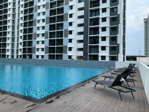 a swimming pool with two chairs and two tall buildings at Desaru Utama Apartment with Swimming Pool View, Karaoke, FREE WIFI, Netflix, near to Car Park in Desaru