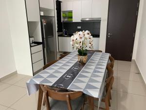 a kitchen with a table with a vase of flowers on it at Desaru Utama Apartment with Swimming Pool View, Karaoke, FREE WIFI, Netflix, near to Car Park in Desaru