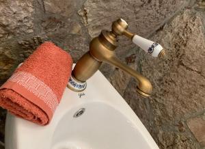 mosiężny kran z czerwonym ręcznikiem na górze toalety w obiekcie Ballkon Turi w Tiranie
