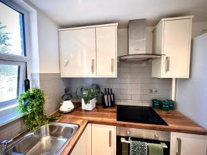 a kitchen with white cabinets and a sink at Room with private bathroom/Tv in Purley