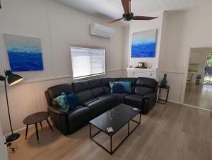 a living room with a black couch and a ceiling fan at Waterside Retreat - Blackies Beach - Swansea Channel in Blacksmiths