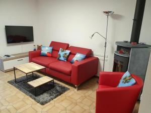 ein Wohnzimmer mit einem roten Sofa und 2 Stühlen in der Unterkunft Casa Ghiggi - Zweizimmerwohnung "Ticino" in Brissago
