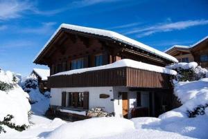 dom pokryty śniegiem w obiekcie Chalet Tannegg Studio im Berneroberland w mieście Reichenbach