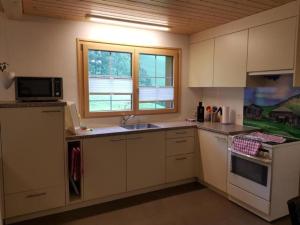 a kitchen with white cabinets and a sink and a window at Ferien im Gugger - Wohnung Stockberg in Nesslau