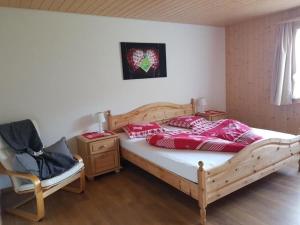 ein Schlafzimmer mit einem Bett mit roten Kissen und einem Stuhl in der Unterkunft Ferien im Gugger - Wohnung Stockberg in Nesslau