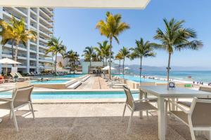a view of the pool at a resort with palm trees and the ocean at Beachfront & free daily breakfast & 600MB 7010 Wifi by Moikkarentals in Puerto Vallarta