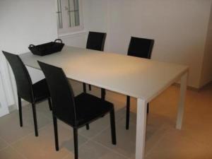 - une table à manger avec des chaises noires et une table blanche dans l'établissement Casa al Lago, à Muralto