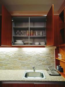 a kitchen with a sink and a shelf with dishes at Prima at Primavera Residences in Cagayan de Oro