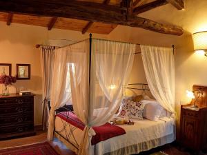 a bedroom with a canopy bed with white curtains at Agriturismo Fattoria La Prugnola in Montescudaio
