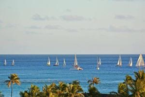 a group of sailboats in the ocean with palm trees at Modern Studio - Heart of Waikiki with Parking! in Honolulu