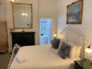 a bedroom with a white bed with a mirror and a fireplace at Accommodation in Fremantle in Fremantle