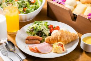 una mesa con un plato de comida con ensalada y pan en Hotel Gracery Shinjuku en Tokio