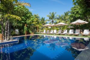 una piscina in un resort con sedie e ombrelloni di Refúgio da Vila Boutique Hotel & SPA a Praia do Forte