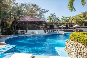 una piscina en un complejo con gente sentada en sillas en Hotel Hacienda del Mar, en Carrillo