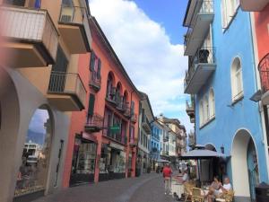 una strada con edifici colorati e persone sedute ai tavoli di Casa alle Vigne Apt 101 ad Ascona