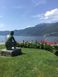una statua seduta nell'erba vicino a un corpo d'acqua di Casa alle Vigne Apt 101 ad Ascona
