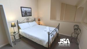 a bedroom with a white bed with a black frame at Razorback 2 in Jindabyne