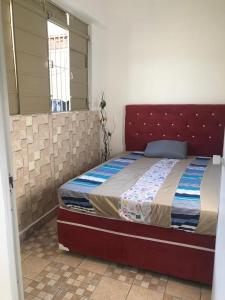 een slaapkamer met een bed met een rood hoofdeinde bij Hostel Celine in São Bernardo do Campo