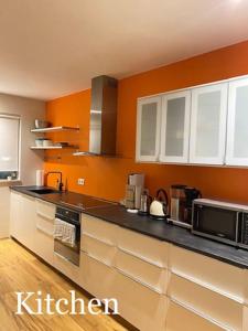 uma cozinha com paredes cor de laranja e uma bancada preta em Spacious 3 bedroom apartment,close to centrum. em Reykjavík