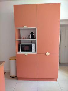 um armário laranja com um micro-ondas na cozinha em Logement meublé au calme em Vertrieu