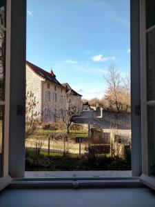 uma janela aberta com vista para um edifício em Logement meublé au calme em Vertrieu