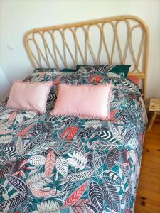 a bed with a colorful comforter and two pink pillows at Logement meublé au calme in Vertrieu