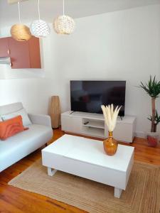 uma sala de estar com uma televisão e uma mesa de centro branca em Logement meublé au calme em Vertrieu