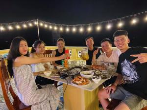 un grupo de personas sentadas alrededor de una mesa con comida en T'H Homestay, en Mui Ne