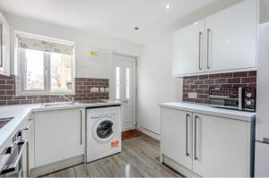 a kitchen with white cabinets and a washer and dryer at Entire House - Three Bed House in Peckham in London