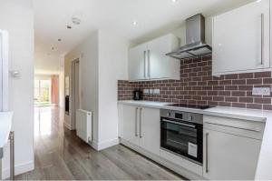 a kitchen with white cabinets and a brick wall at Entire House - Three Bed House in Peckham in London