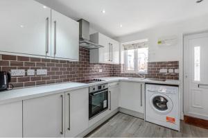 a kitchen with white cabinets and a washer and dryer at Entire House - Three Bed House in Peckham in London