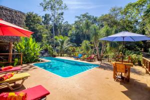 a resort pool with chairs and an umbrella at Mariposa Jungle Lodge in San Ignacio