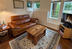 ein Wohnzimmer mit einem Ledersofa und einem Couchtisch in der Unterkunft Liahona Guest House in Ucluelet